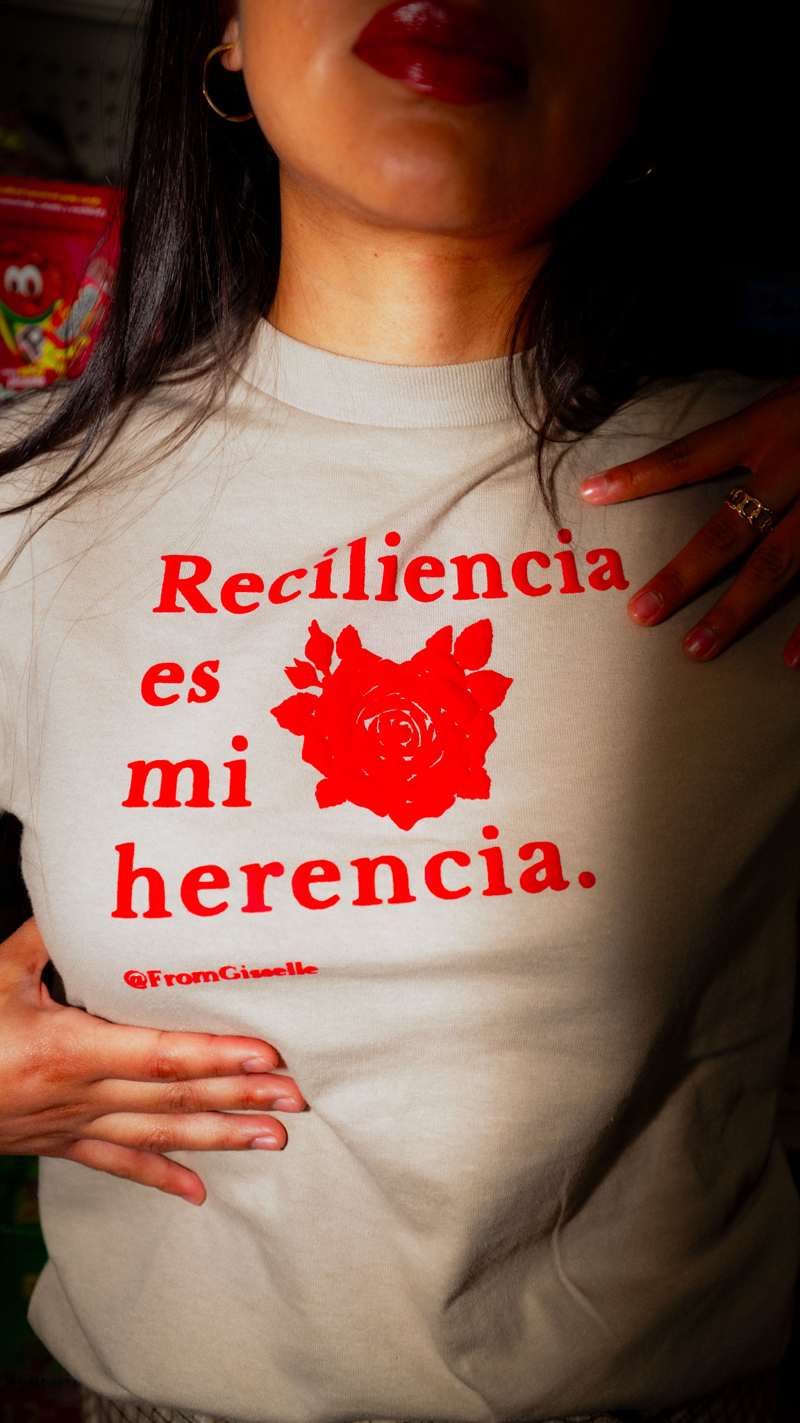A beige long sleeve shirt with 'Resiliencia Es Mi Herencia' printed in deep red.